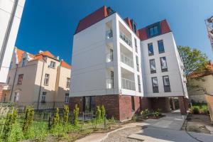 een hoog wit gebouw met een rood dak bij Golden Apartments Gdansk&K2A in Gdańsk