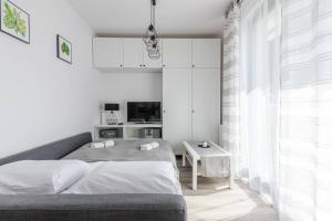 een witte slaapkamer met een bed en een tafel bij Golden Apartments Gdansk&K2A in Gdańsk