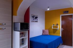 a small room with a blue bed and a microwave at Miky's Flat in Marciana