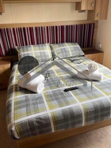 a bed with two pillows and a book on it at Tranquility - Static Caravan Lune Park on Parkdean Ocean Edge Resort in Heysham