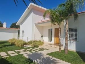 a white house with palm trees in front of it at La Maison - Boutique Rooms in Sperlonga