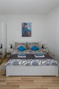 a white bedroom with a large bed with blue pillows at Apartment Pemper - Self check in and check out in Otočac