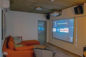 a living room with a couch and a large screen at הרימון- צימר בוטיק לזוג במעלה גמלא in Ma'ale Gamla