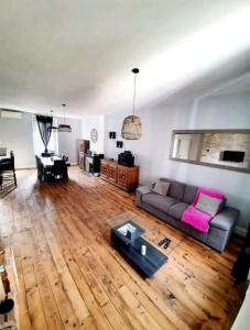 a living room with a couch and a wooden floor at Spacieux Cosy in Blaye-les-Mines