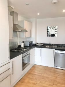 a kitchen with white cabinets and stainless steel appliances at Bedford Central Apartment with Free Secure Parking in Bedford