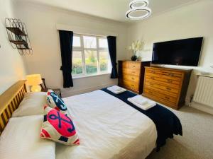 a bedroom with a bed and a dresser with a television at Sandy Shores, 3 min walk to beach & Swanage centre in Ulwell