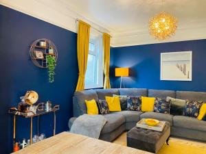 a blue living room with a gray couch and yellow pillows at Sandy Shores, 3 min walk to beach & Swanage centre in Ulwell