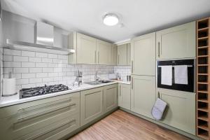 a kitchen with white cabinets and a stove at Chic & Contemporary Apartment with Patio - Parking in Wakefield