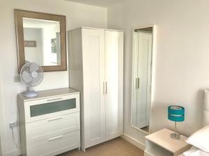 a bedroom with a white dresser and a mirror at Bedford Central Apartment with Free Secure Parking in Bedford