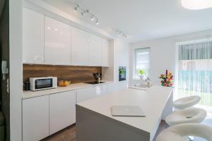 a kitchen with white cabinets and a white counter top at Luxus Partivilla Apartman in Szántód
