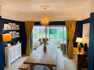 a dining room with a wooden table and yellow curtains at Sandy Shores, 3 min walk to beach & Swanage centre in Ulwell