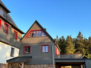 een huis met een gambrel dak en rode ramen bij Chalet Zugspitze in Kurort Altenberg