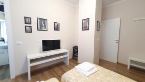 Sala de estar blanca con TV y mesa en RomagnaBNB Cignani en Forlì