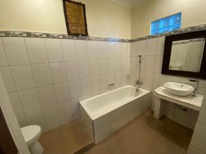 La salle de bains est pourvue d'une baignoire, d'un lavabo et de toilettes. dans l'établissement Brata Inn Ubud, à Ubud