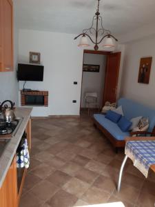 a living room with a blue couch and a kitchen at Ambrosia casa vacanza " Giada " in Orosei