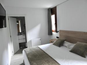 Apartaments Turistics El Buner في أوردينو: غرفة نوم بسرير ابيض كبير مع وسادتين