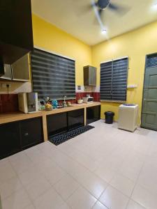 a large kitchen with yellow walls and white tile floors at D Embun Homestay in Pasir Mas