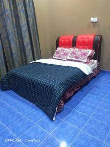 uma cama com um cobertor preto e vermelho e almofadas em D Embun Homestay em Pasir Mas