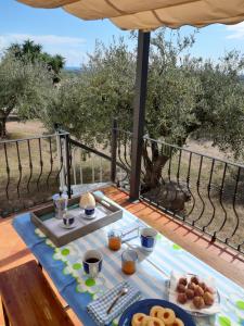 a breakfast table on a deck with a view of the olive trees at Ambrosia casa vacanza " Giada " in Orosei