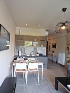 a kitchen with a table and white chairs in a room at Palaia premium flat in Volos