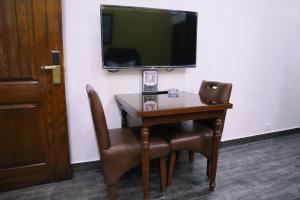 a desk with two chairs and a television on a wall at Hayyat Luxury Suites in Lahore