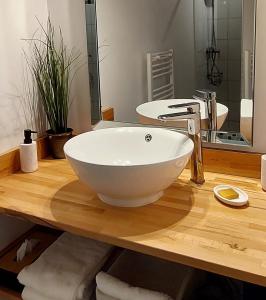 ein Badezimmer mit einem weißen Waschbecken auf einer Holztheke in der Unterkunft Le Clos des Roses in Parçay-les-Pins