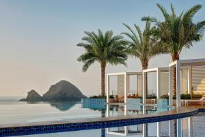 een zwembad met palmbomen en uitzicht op de oceaan bij Royal M Al Aqah Beach Resort by Gewan in Al Aqah