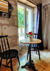 - une table et deux chaises dans une chambre avec fenêtre dans l'établissement Le Clos des Roses, à Parçay-les-Pins