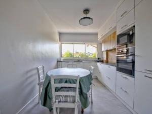 アルカションにあるAppartement Arcachon, 5 pièces, 10 personnes - FR-1-433-28の白いキャビネット、テーブルと椅子付きのキッチンが備わります。