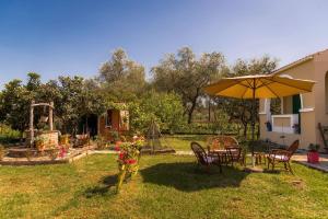 a backyard with a table and chairs and an umbrella at Yellow Bike House in Lefkímmi