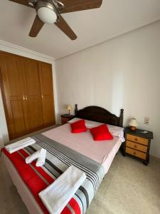 una camera da letto con letto, cuscini rossi e soffitto di Apartamento en Arenals Del Sol ad Arenales del Sol