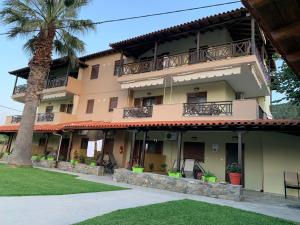 a building with a palm tree in front of it at Katerina-Maria Studios & Apartments in Vourvourou