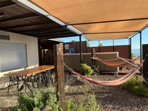 a hammock and a table and bench under a roof at הרימון- צימר בוטיק לזוג במעלה גמלא in Ma'ale Gamla