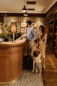 a man and a woman and a child with a suitcase at Andrássy Kúria & Spa in Tarcal