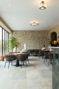 two people sitting at tables in a restaurant with a stone wall at Andrássy Kúria & Spa in Tarcal