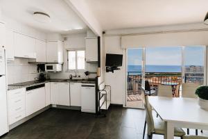 uma cozinha com armários brancos e uma mesa com vista em Trevol 2 linea del mar em Platja d'Aro