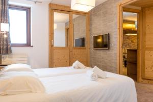 dwa białe łóżka w pokoju z telewizorem w obiekcie Résidence Koh-I Nor by Les Etincelles w Val Thorens