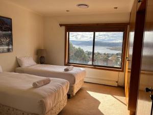 a room with two beds and a large window at Top Deck by Kristall Apartments in Jindabyne