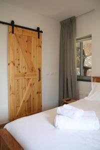 a bedroom with a bed with a sliding barn door at הרימון- צימר בוטיק לזוג במעלה גמלא in Ma'ale Gamla +32 photos