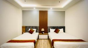 two beds in a room with white walls at Win Villa Hotel & Apartment in Hanoi