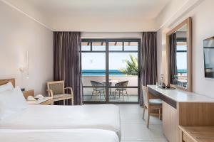 a hotel room with a bed and a view of the ocean at Porto Platanias Beach Resort & Spa in Plataniás