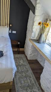 a bedroom with a bed and a vase with flowers on a table at Romantic Hideaway in Trawsfynydd