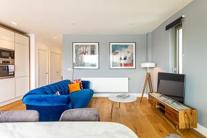 a living room with a blue couch and a tv at Stunning Surrey Quays Flat in London