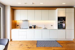 a kitchen with white cabinets and a rug at Stunning Surrey Quays Flat in London