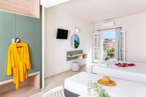 una camera con un letto e un tavolo con una giacca gialla appesa a un muro di Sunshine Studios a Mália