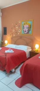 a bedroom with two beds with red sheets and a painting at Estía Holidays Apartments - Taormina in Taormina