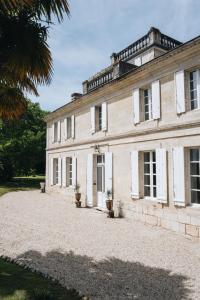 Cette ancienne maison en pierre est dotée de portes et de fenêtres blanches. dans l'établissement Le Château Réal, à Saint-Seurin-de-Cadourne