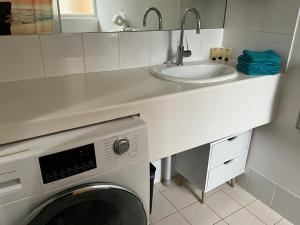 a kitchen with a washing machine and a sink at Lovely "Driftwood Taft" Apartment Beach & Everything few Minutes walk! Central Glenelg in Glenelg +10 photos