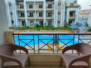 a balcony with two chairs and a swimming pool at قريه لاسرينا العين السخنة in Ain Sokhna
