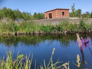a building sitting next to a body of water at Mamucia Chata in Kaszuba +3 photos